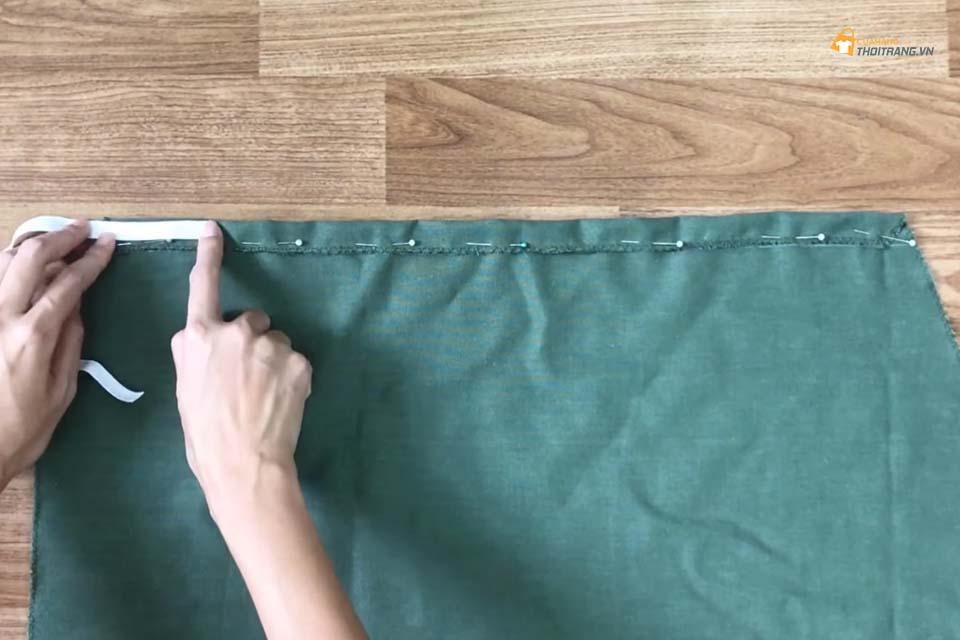Từ đỉnh của mảnh vải, vẽ một đường nằm ngang cách đó 4cm. Sau đó gấp vải theo đường đó và may lại rồi lồng chun